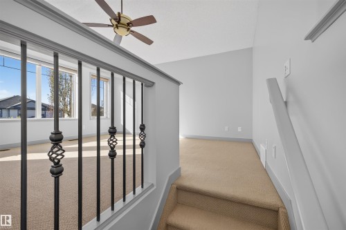 Open-concept landing with decorative wrought iron railing and a ceiling fan - 6116 8 Avenue Sw, Edmonton, AB 