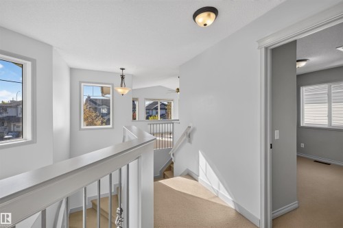 Carpeted upper landing with painted balusters, multiple windows, and recessed lighting - 6116 8 Avenue Sw, Edmonton, AB 