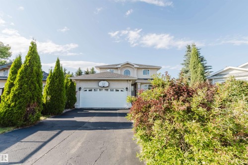 Two-story residence featuring a two-car garage, paved driveway, and mature landscaping - 11526 9 Avenue Nw, Edmonton, AB 