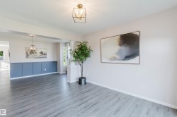 Wide plank wood-finish flooring, two-tone wall paneling, modern pendant lighting, recessed lighting, and ample natural light - 