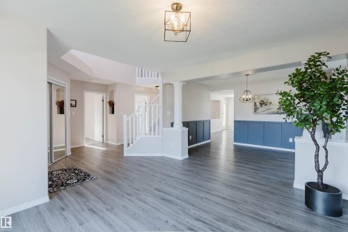 Wood-finish flooring throughout, white painted staircase, built-in paneling, and an open layout - 11526 9 Avenue Nw, Edmonton, AB 