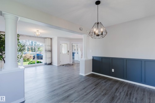 Wood-finish flooring throughout, decorative wainscoting, and a geometric pendant light fixture - 11526 9 Avenue Nw, Edmonton, AB 