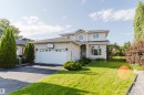 Stucco exterior with a two-car garage, arched entry, bay window, and a well-maintained lawn - 11526 9 Avenue Nw, Edmonton, AB 