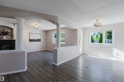 Wood-finish flooring throughout, framed by architectural columns and an archway - 