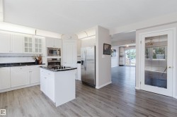 Kitchen featuring white cabinetry, dark countertops, wood-finish flooring, a stainless steel refrigerator, and built-in microwave - 