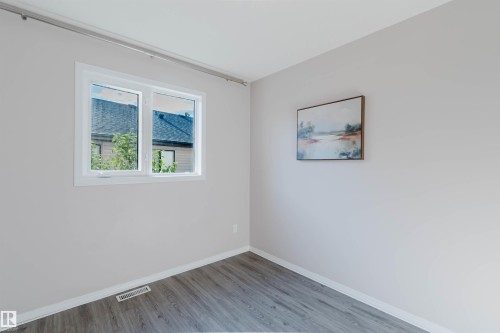 Wood-finish flooring with white trim, a double-pane window, and light neutral wall finishes - 11526 9 Avenue Nw, Edmonton, AB 