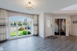Arched picture window, wood-finish flooring, white entry door with decorative glass, mirrored closet doors, and a geometric flush-mount light fixture - 