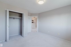 Neutral-toned room featuring a flush-mount ceiling light, light-colored carpeting, and a bi-fold door closet with a hanging rod - 