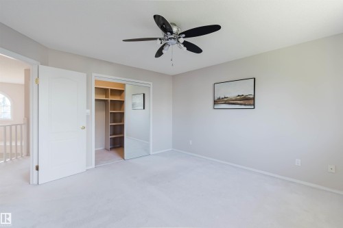 Ceiling fan with light, wall-to-wall carpeting, bi-fold mirrored closet doors, built-in closet shelving, and a paneled interior door - 11526 9 Avenue Nw, Edmonton, AB 