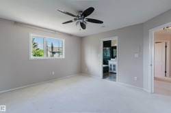 Spacious room with light-colored carpeting, a ceiling fan, and a large window - 
