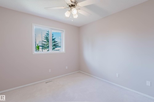 Neutral-toned walls with light-colored carpeting, featuring a window with white trim, and a ceiling fan with integrated lighting - 11526 9 Avenue Nw, Edmonton, AB 