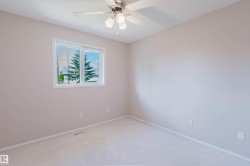 Neutral-toned walls with light-colored carpeting, featuring a window with white trim, and a ceiling fan with integrated lighting - 