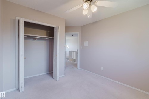 Light-toned walls, carpeted flooring, bi-fold closet, and a ceiling fan with integrated lighting - 11526 9 Avenue Nw, Edmonton, AB 
