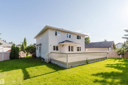Expansive backyard featuring a manicured lawn, a large wood-finish deck with lattice skirting, and a stucco exterior - 11526 9 Avenue Nw, Edmonton, AB 