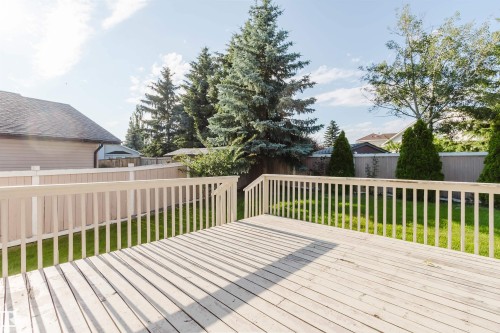 Expansive outdoor deck with white railing, overlooking a fenced yard and mature trees - 11526 9 Avenue Nw, Edmonton, AB 