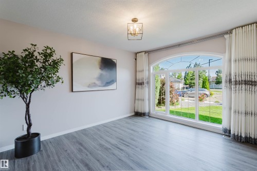Arch-top window with multi-pane design, wood-finish flooring, and a decorative ceiling light fixture - 11526 9 Avenue Nw, Edmonton, AB 