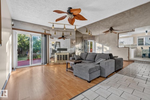 Light wood-finish flooring, sliding glass door leading to a red-painted deck, white tile flooring, ceiling fan with leaf-shaped blades, and track lighting - 11 Howson Crescent Nw, Edmonton, AB 