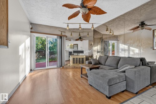 Wood-finish flooring, sliding glass door to exterior, mirrored accent wall, built-in fireplace, and overhead lighting fixtures - 11 Howson Crescent Nw, Edmonton, AB 