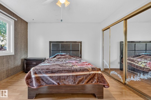 Wood-finish flooring, accent wall, mirrored closet doors, and a ceiling fan - 11 Howson Crescent Nw, Edmonton, AB 