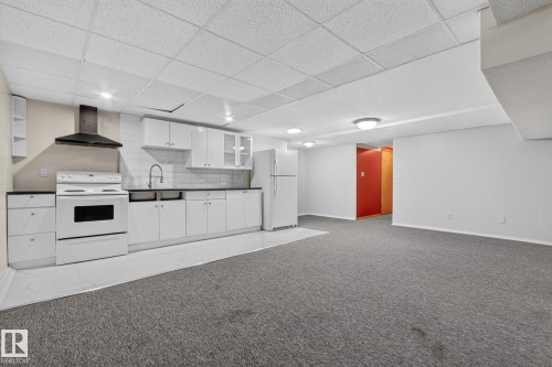 Full kitchen with white cabinetry, dark countertops, white tile backsplash, and a black range hood - 11 Howson Crescent Nw, Edmonton, AB 