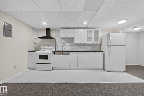 Kitchenette with white cabinetry, dark countertops, white tile backsplash, and a black range hood - 11 Howson Crescent Nw, Edmonton, AB 