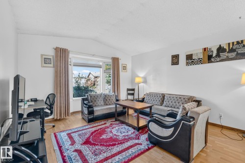 Bright living area featuring wood-finish flooring, white walls, and a large window - 11 Howson Crescent Nw, Edmonton, AB 