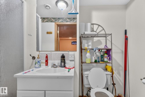 White vanity with integrated sink, wall-mounted mirror, and overhead light fixture - 11 Howson Crescent Nw, Edmonton, AB 