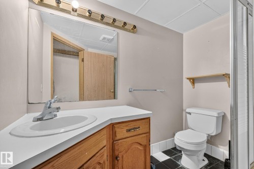 Vanity with integrated sink, wood-finish cabinetry, and overhead lighting - 11 Howson Crescent Nw, Edmonton, AB 