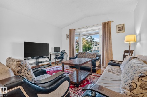 Bright living area with a bay window, wood-finish flooring, and crisp white walls - 11 Howson Crescent Nw, Edmonton, AB 