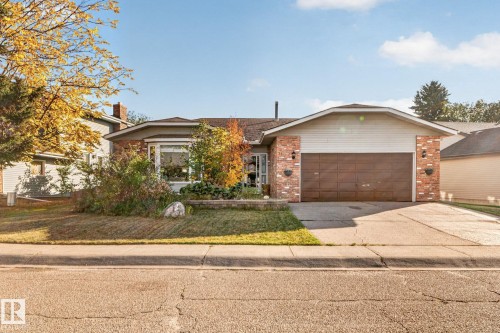 Brick and siding exterior with an integrated garage, featuring a bay window, established landscaping, and a concrete driveway - 11 Howson Crescent Nw, Edmonton, AB 