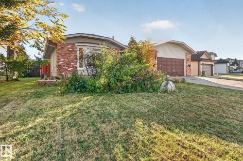 Brick and siding exterior with a curved bay window, attached garage with a panel door, and established landscaping - 11 Howson Crescent Nw, Edmonton, AB 