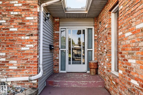 Brick exterior with gray siding accents, glass panel entry door, and an overhead skylight - 11 Howson Crescent Nw, Edmonton, AB 
