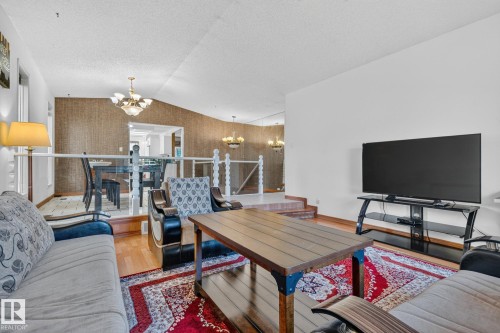 Spacious living area featuring hardwood flooring, white walls, and a glass-paneled railing - 11 Howson Crescent Nw, Edmonton, AB 