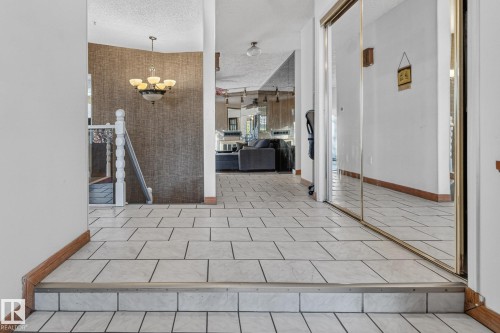 Tiled flooring throughout, mirrored closet doors, and a decorative chandelier - 11 Howson Crescent Nw, Edmonton, AB 