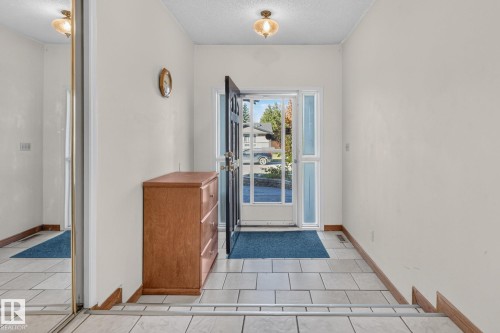 Entryway featuring tile flooring, a solid panel entry door with clear glass sidelights, and a flush mount ceiling fixture - 11 Howson Crescent Nw, Edmonton, AB 