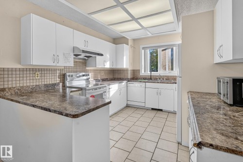 White cabinetry, tile flooring, stone-finish countertops, tile backsplash, and a built-in oven range - 11 Howson Crescent Nw, Edmonton, AB 