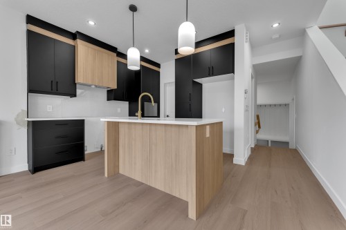 Kitchen featuring a central island with a light wood-finish base, white countertop, and gold-tone faucet - 58 Silverstone Drive, Stony Plain, AB 