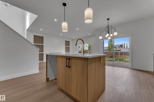 Kitchen island with wood-finish cabinetry and a light-toned countertop, featuring a brass-finish faucet - 58 Silverstone Drive, Stony Plain, AB 