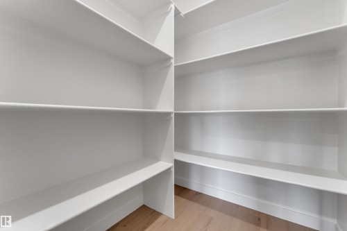 Integrated shelving system with multiple white shelves and light wood-finish flooring - 58 Silverstone Drive, Stony Plain, AB 