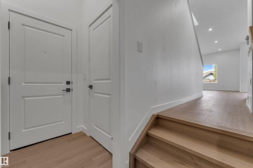 Wood-finish flooring throughout, white paneled doors with matte black hardware, and recessed ceiling lighting - 58 Silverstone Drive, Stony Plain, AB 