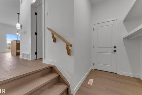 Wood-finish flooring throughout, white walls, and a wood handrail - 58 Silverstone Drive, Stony Plain, AB 