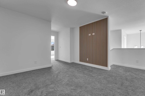 Carpeted living space featuring a wood-panel accent wall and white wall finishes - 58 Silverstone Drive, Stony Plain, AB 