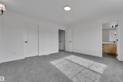 Spacious room featuring gray carpeting, white walls, and a flush-mount ceiling light - 58 Silverstone Drive, Stony Plain, AB 