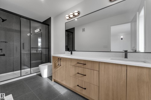 Floating wood-finish vanity with dual integrated sinks, quartz-finish countertop, and matte black fixtures - 58 Silverstone Drive, Stony Plain, AB 