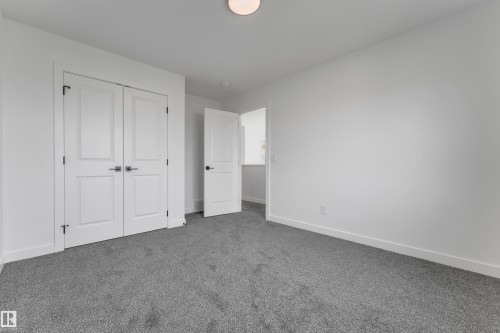 White walls, gray carpeting, a flush mount ceiling light, and white interior doors with dark hardware - 58 Silverstone Drive, Stony Plain, AB 