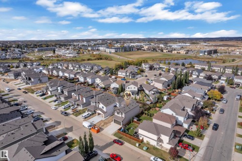 Residential street with multiple single-family homes, paved roads, and a visible pond - 58 Silverstone Drive, Stony Plain, AB 