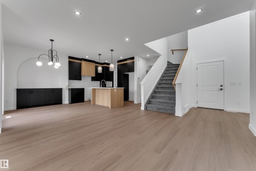 Expansive wood-finish flooring, recessed lighting, and a contemporary kitchen featuring light wood-finish and black cabinetry - 58 Silverstone Drive, Stony Plain, AB 