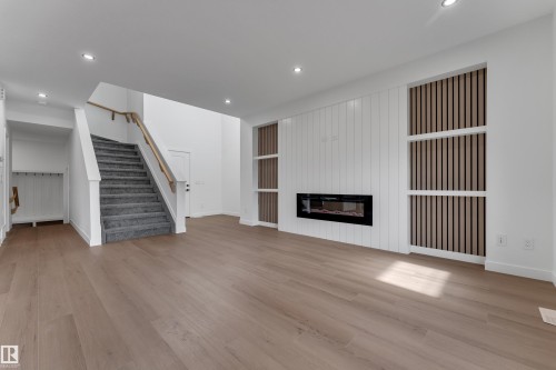 Light wood-finish flooring, recessed lighting, and a modern linear electric fireplace with a shiplap accent wall - 58 Silverstone Drive, Stony Plain, AB 
