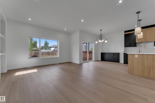Recessed lighting, wood-finish flooring, built-in shelving, sliding glass door, and a kitchen island with pendant lighting - 58 Silverstone Drive, Stony Plain, AB 