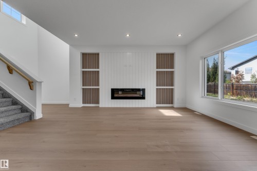 Open-concept living area featuring wood-finish flooring, a contemporary fireplace, and recessed lighting - 58 Silverstone Drive, Stony Plain, AB 